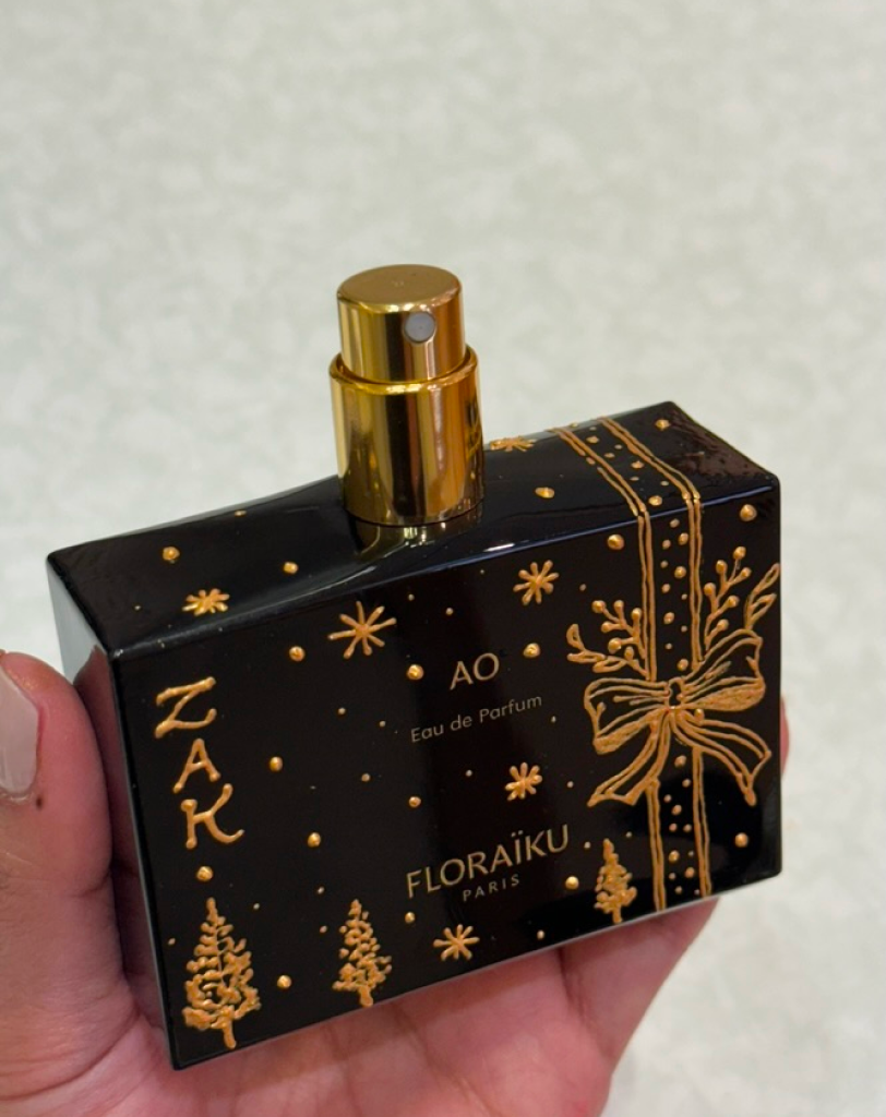 Close-up of Floraïku AO Eau de Parfum with hand-painted gold holiday bow and snowflakes.