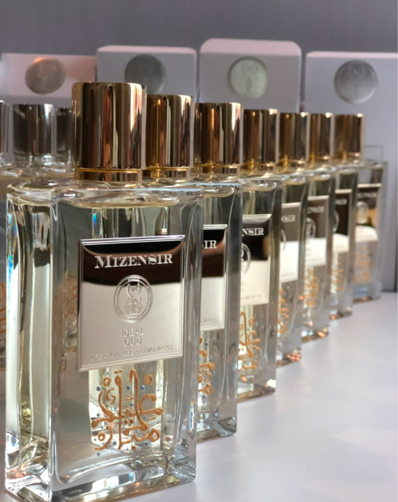 A perspective shot of multiple Mizensir "Ideal Oud" bottles lined up, highlighting the reflective silver labels and the "Creation Alberto Morillas" text.