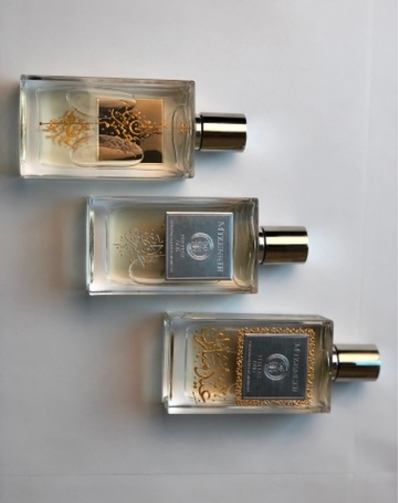 Three Mizensir perfume bottles laid flat on a white surface, showing different label styles including "Perfect Oud" and "Ideal Oud" with varying gold filigree and calligraphy.