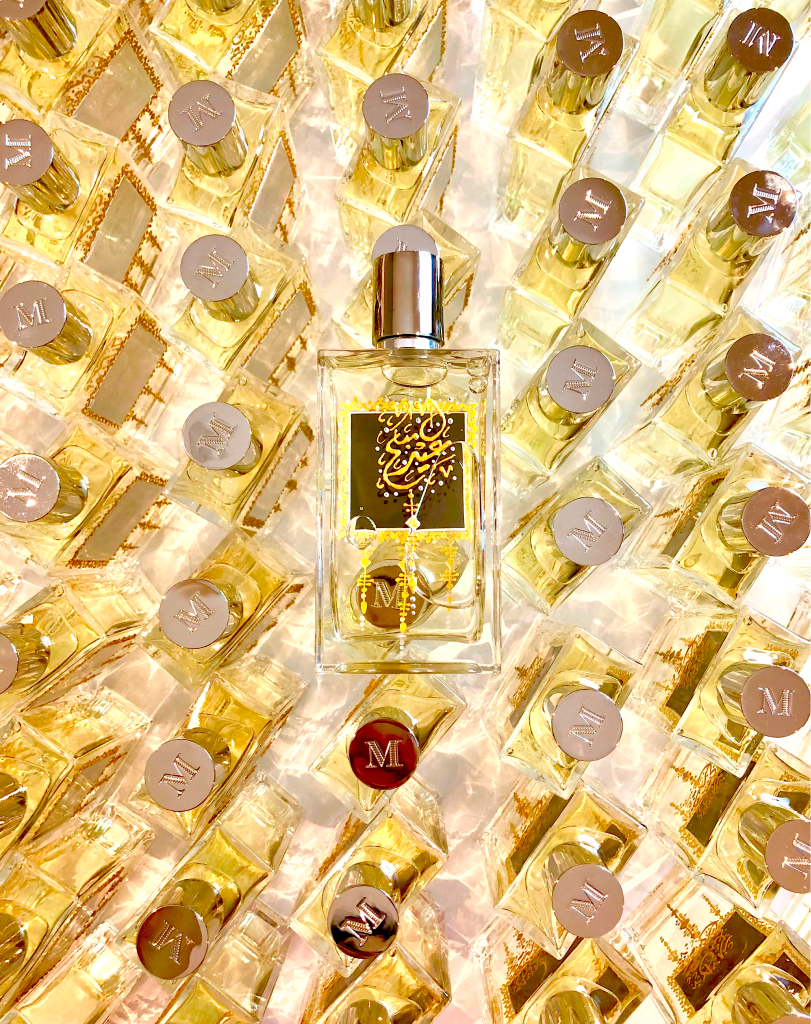 An overhead bird's-eye view of dozens of Mizensir perfume bottles packed together, with a single central bottle featuring a black label and ornate gold calligraphic art.