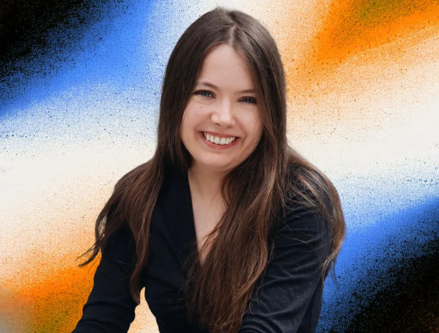 Smiling woman with long brown hair wearing a black top in front of a colorful abstract background with blue, orange, and white hues.