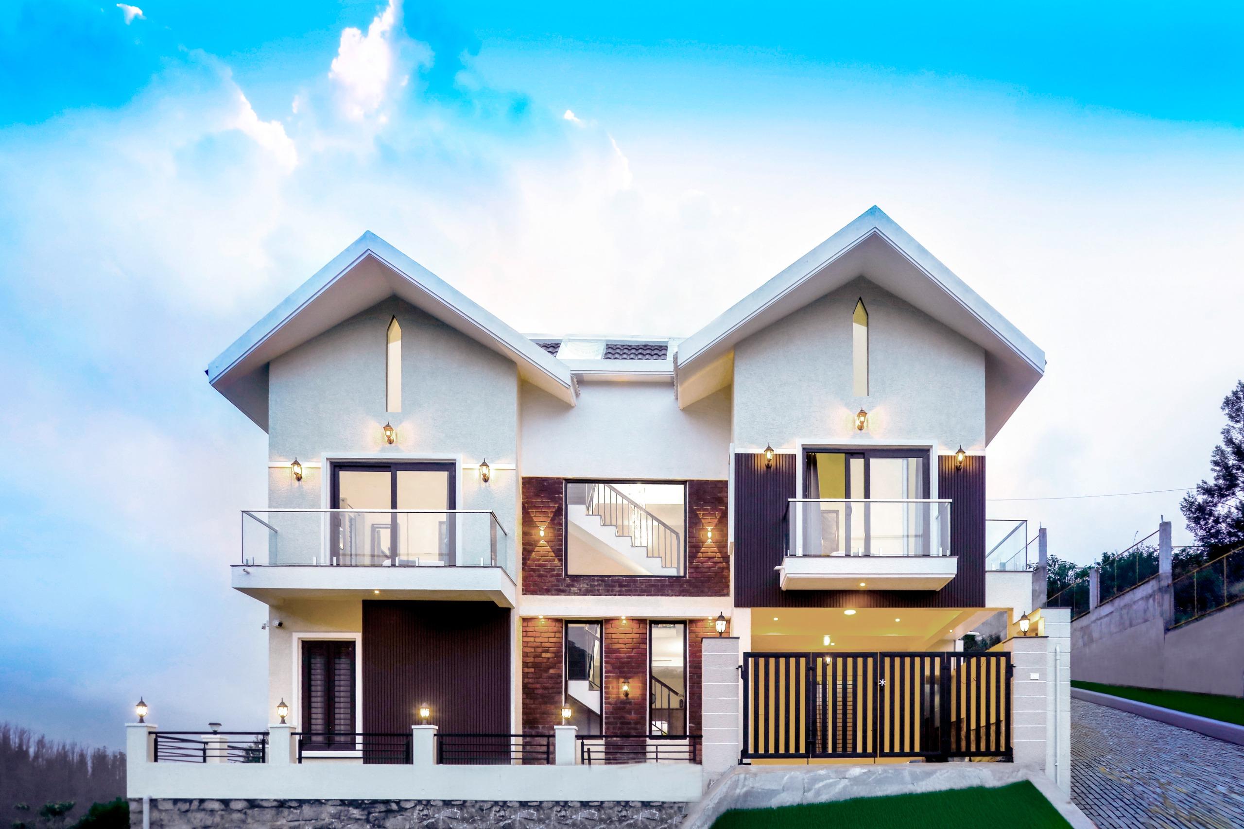 Modern two-story house with symmetrical design, glass balconies, black and white facade, and outdoor lighting.