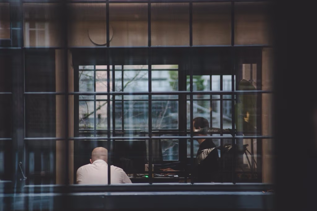 To kolleger i samtale på kontor set gennem vinduer.