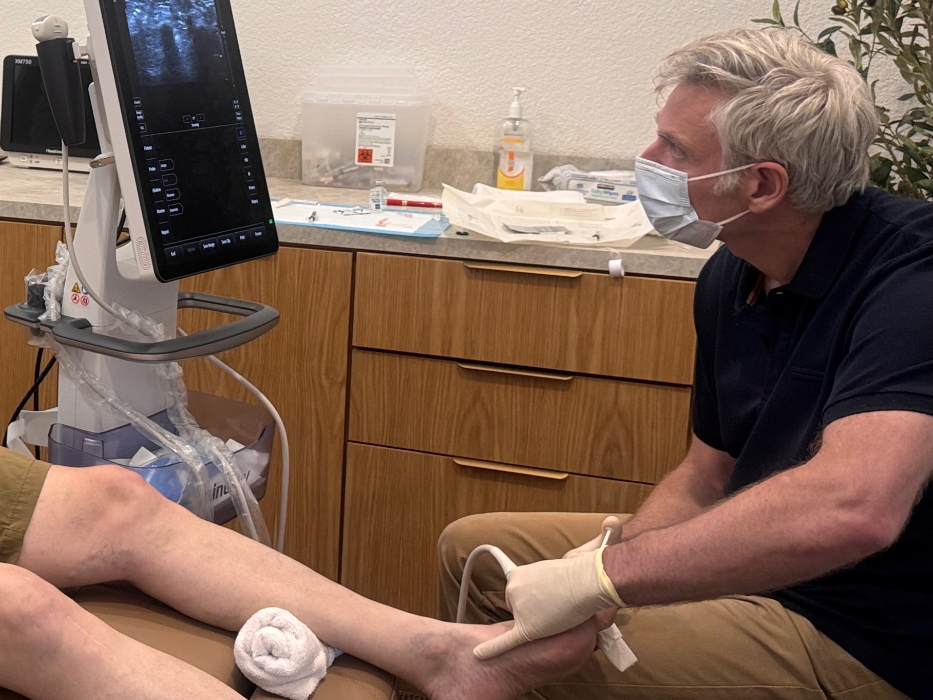 Physician performing ultrasound-guided foot evaluation at Alypos Regenerative Pain and Wellness in Southlake, Texas
