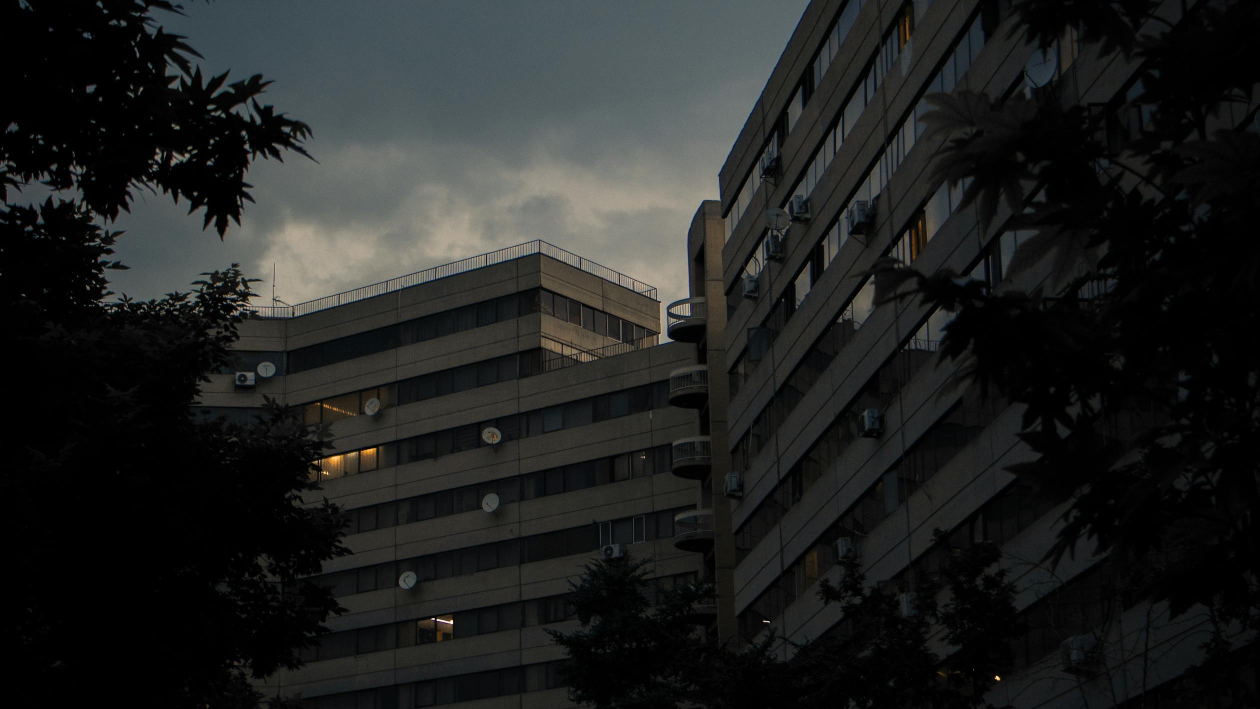 Dark urban building with lit windows at dusk
