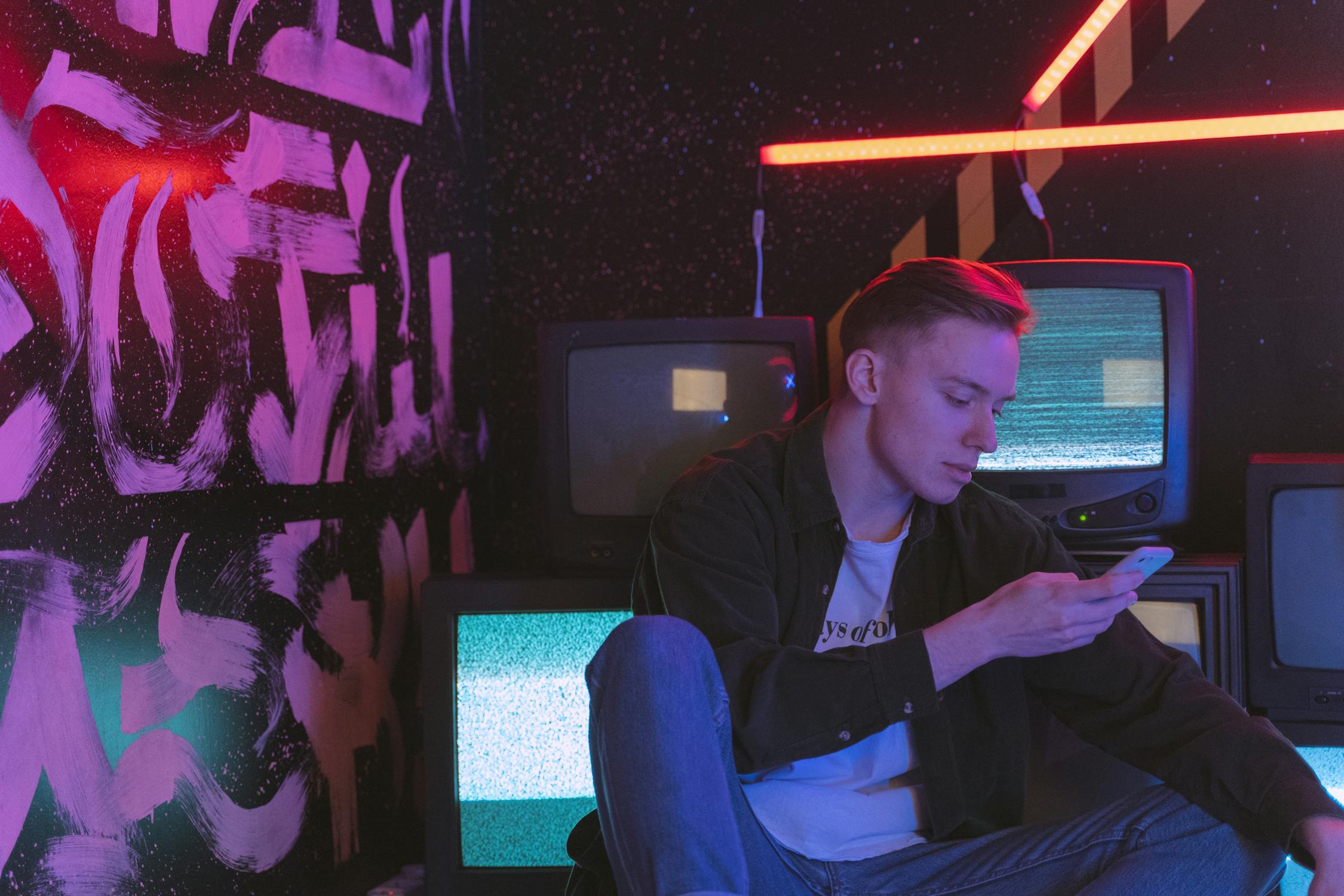 Man using smartphone in neon-lit room