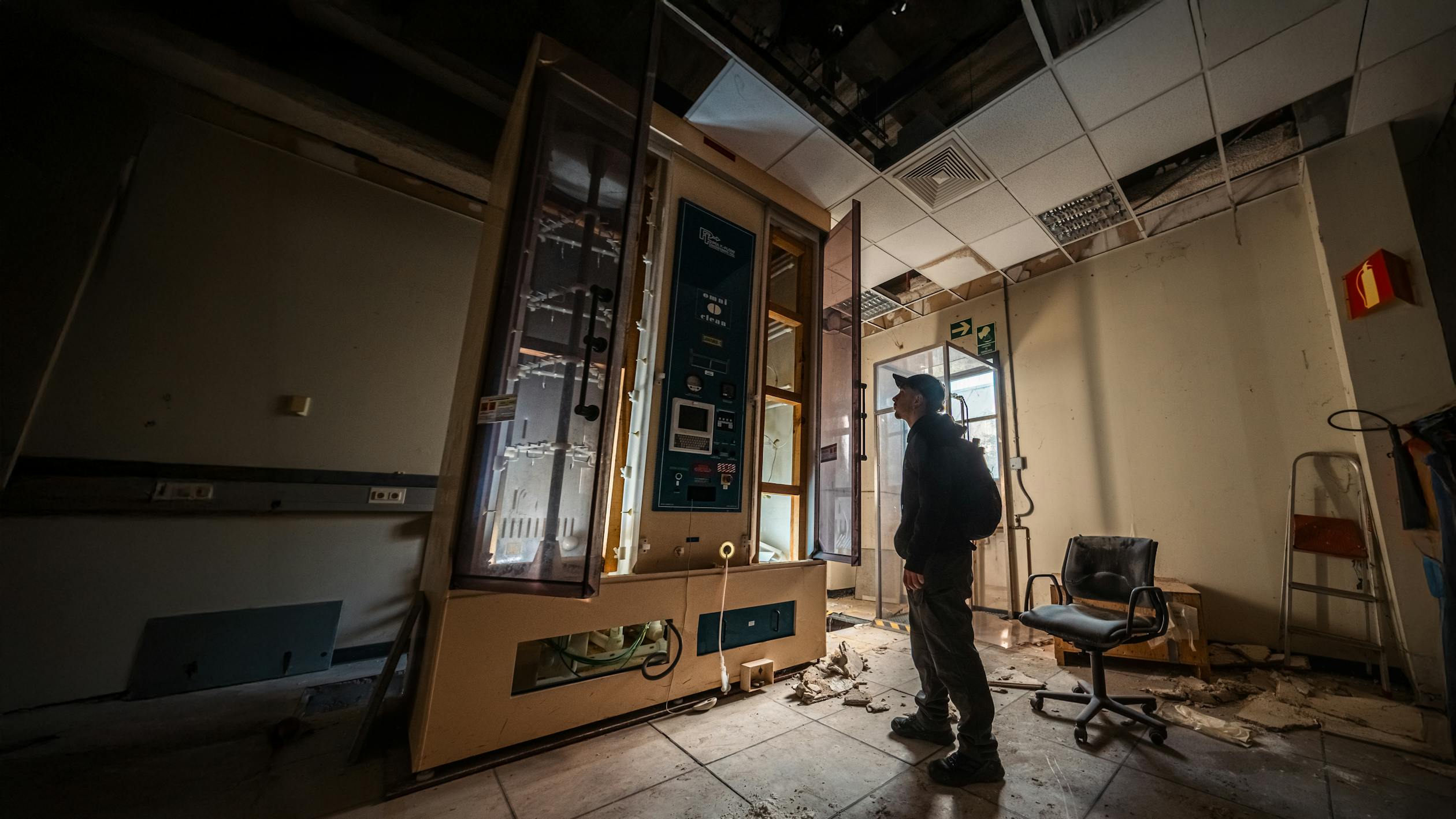 Man examining machinery in dimly lit abandoned facility