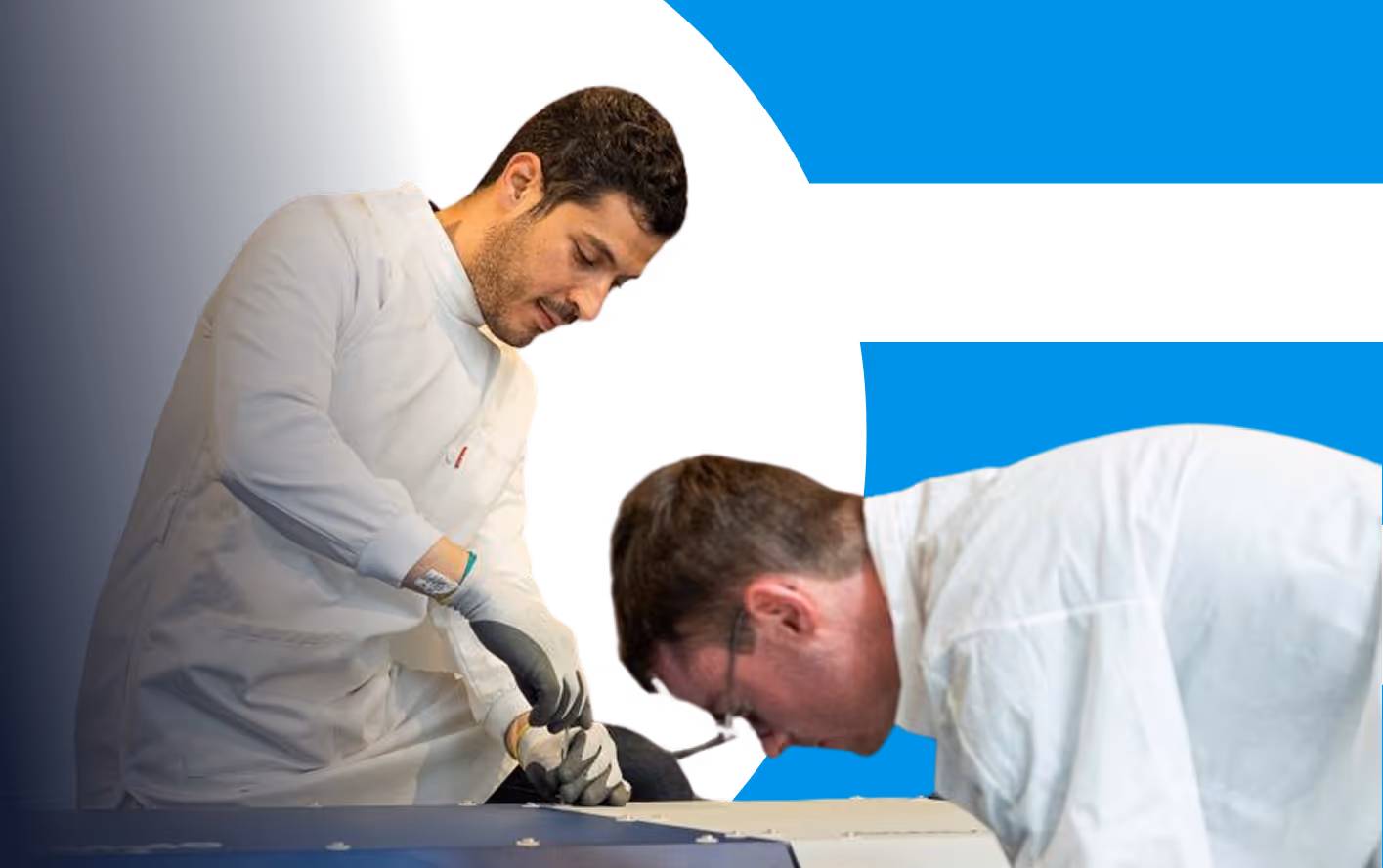 Deux hommes en blouse blanche travaillant avec des gants sur une machine ou un équipement.