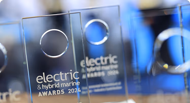 Gros plan sur plusieurs trophées en verre transparent avec des découpes circulaires portant l'inscription « electric & hybrid marine AWARDS 2024 ».