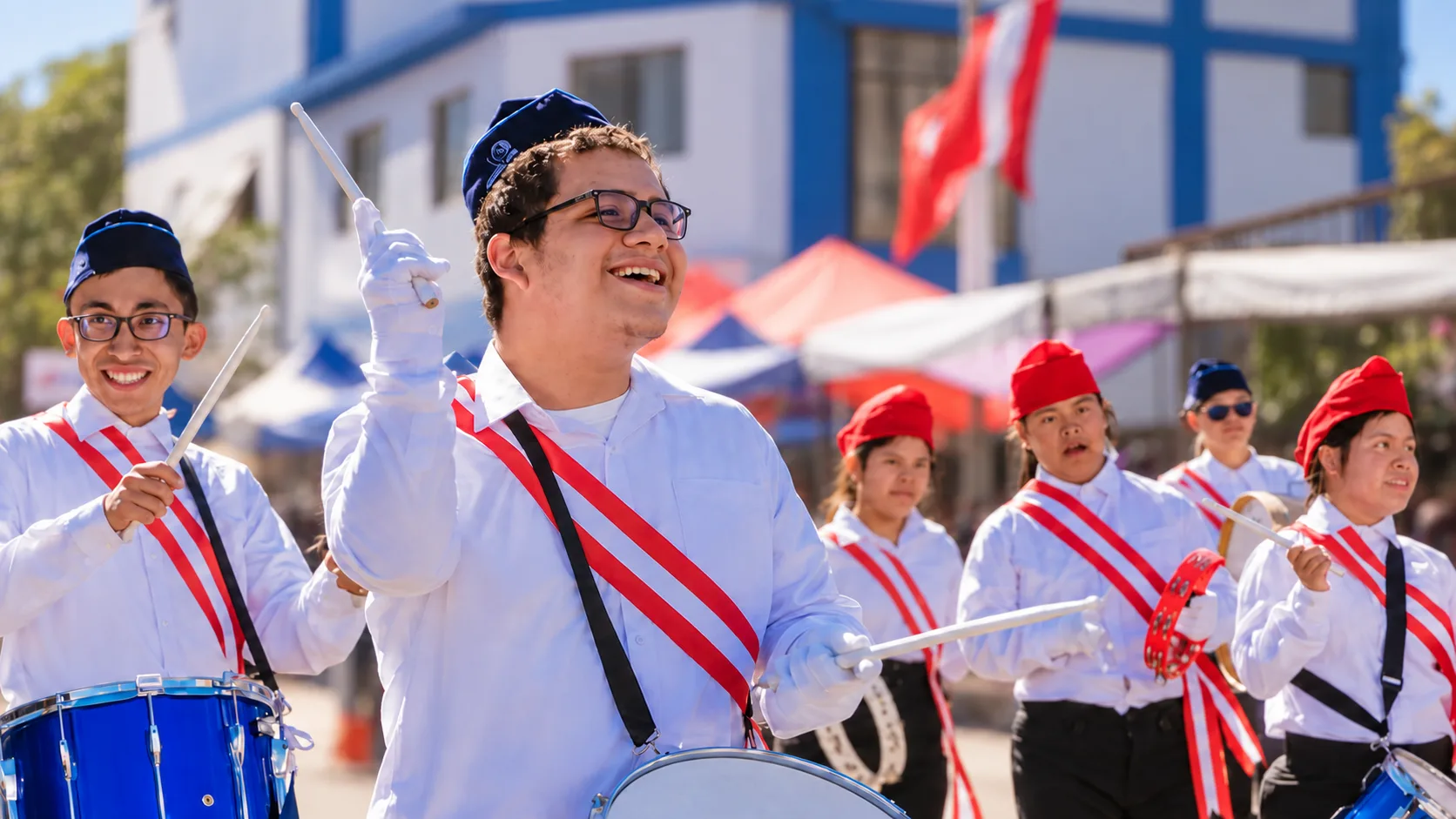 Jugendliche der Banda von Unámonos in weißen Hemden mit rot-weißen Schärpen und Trommeln beim Umzug in Arequipa