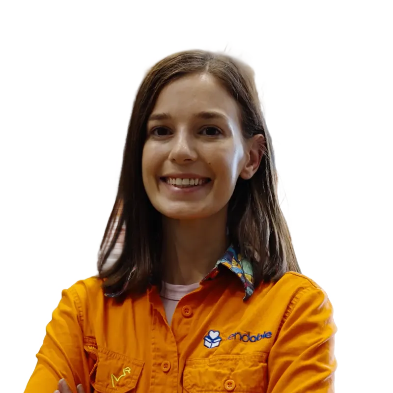 Smiling woman with shoulder-length brown hair wearing an orange button-up shirt with a colorful collar and logo.