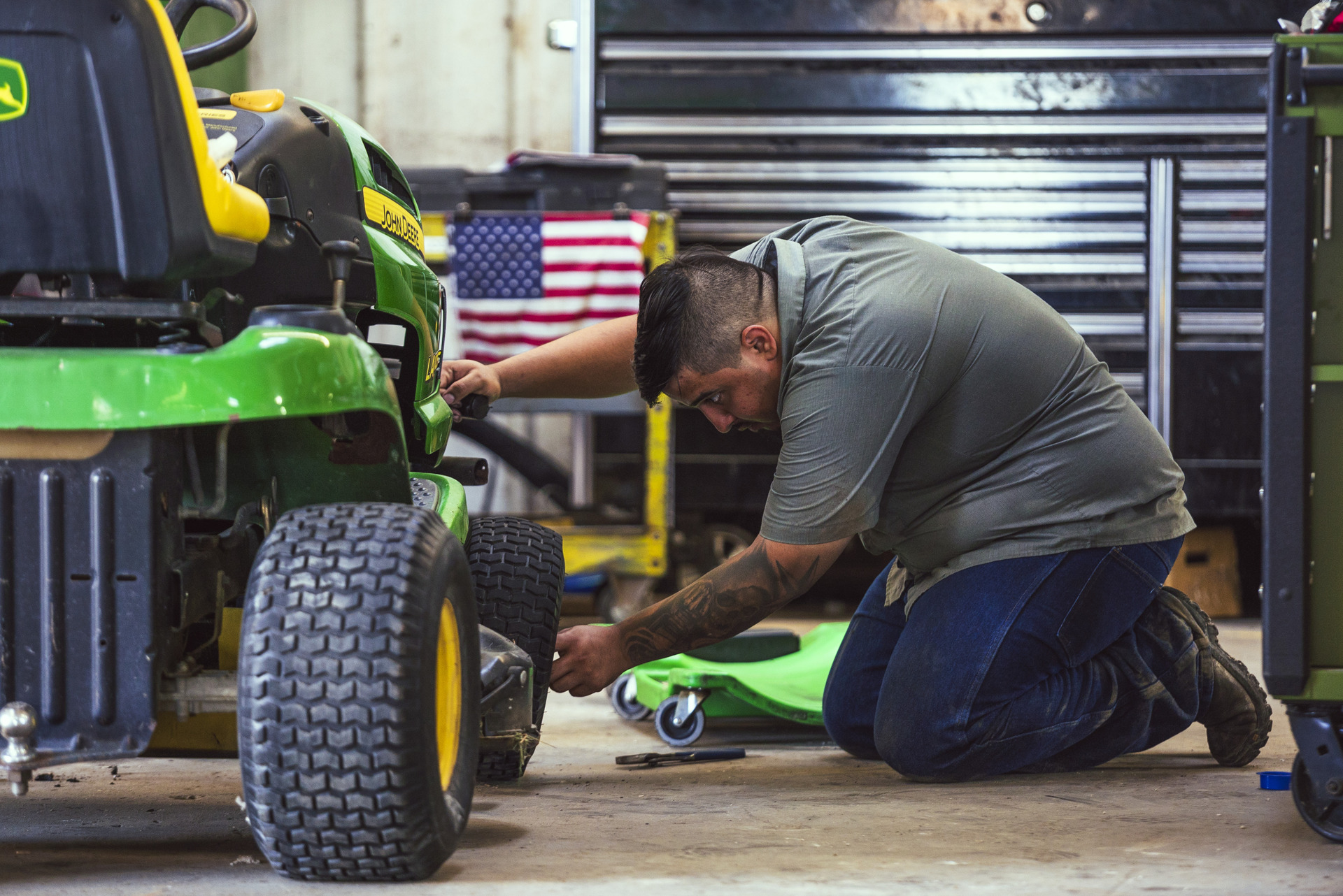 A worker at Tellus Equipment Solutions checks the tire pressure and mower deck of a John Deere mower