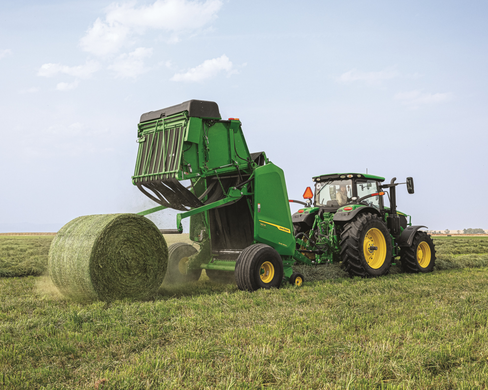 A round baler empties a finished hay bale in a Texas field.