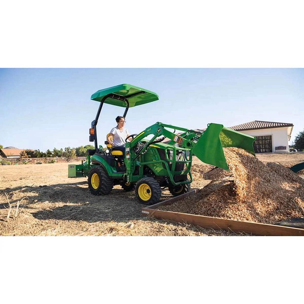 1025R Tractor Sub-Compact Tractors with a farmer driving a tractor with a loader full of hay