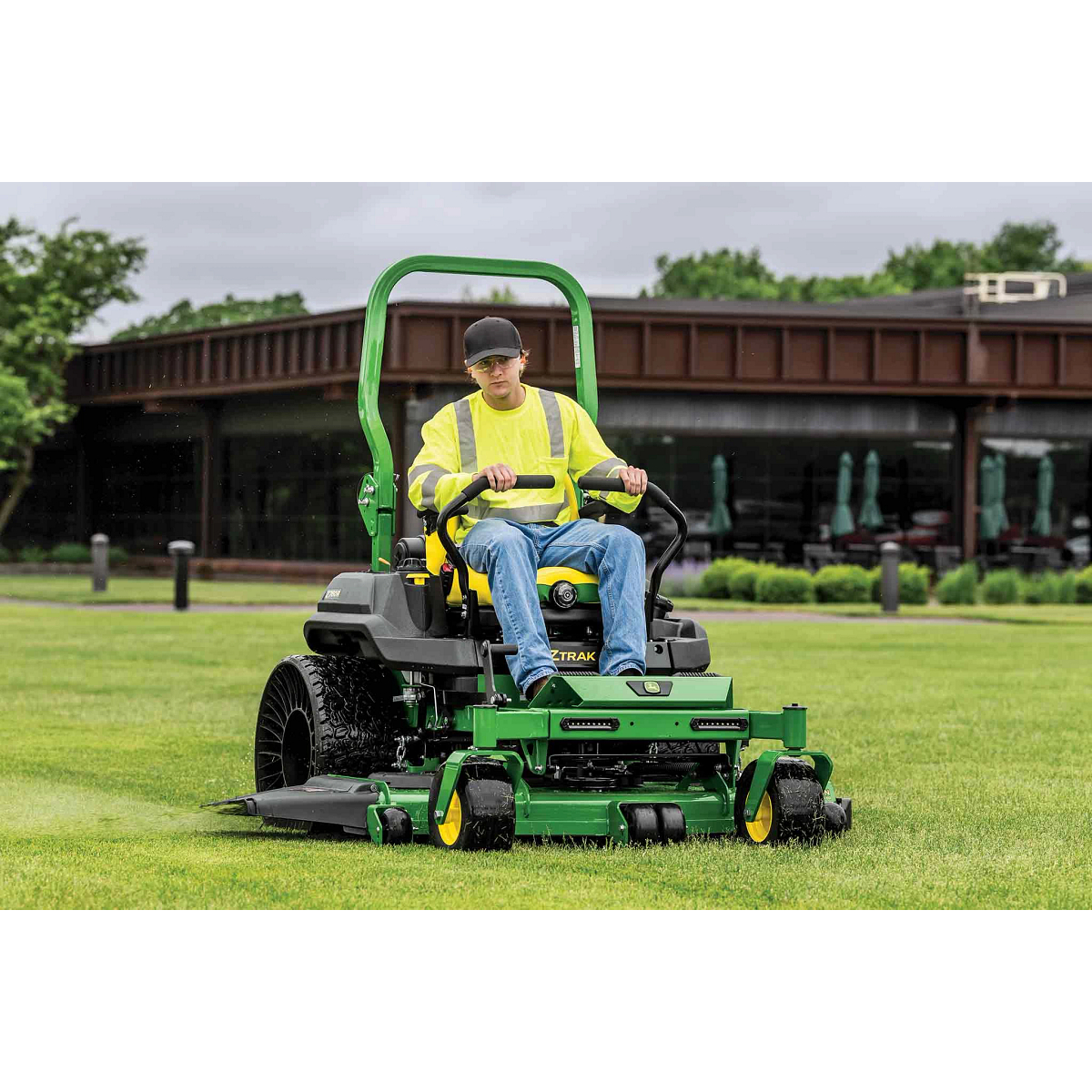 A grounds crew member operates a Z760R zero-turn mower across a large lawn near a commercial building