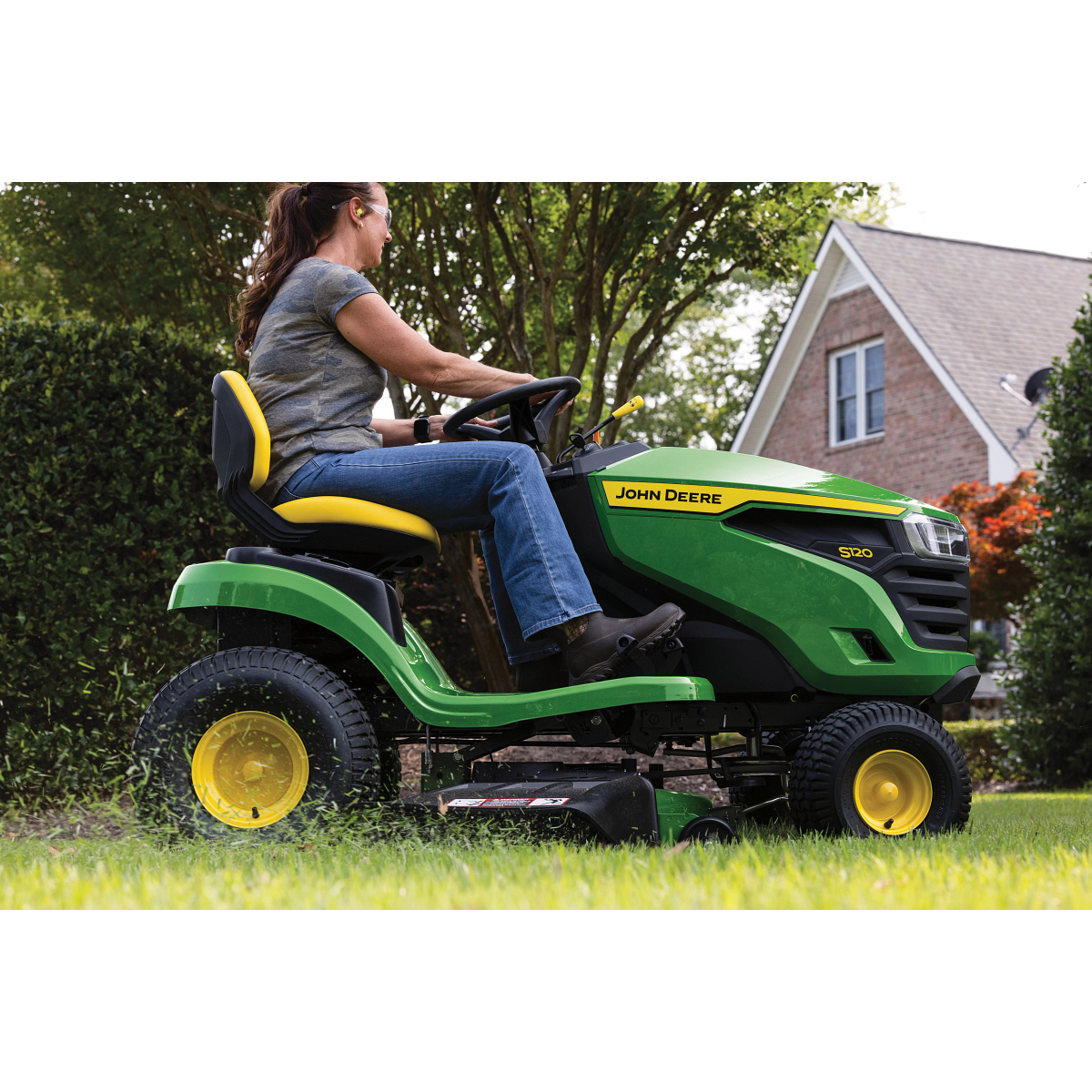 Side right close-up of an operator on an S120 Lawn Tractor on a residential lawn