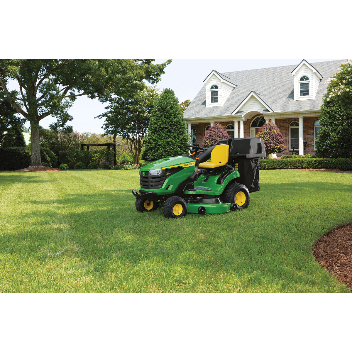 Front left view of an S140 Lawn Tractor with material collection system resting on a residential lawn