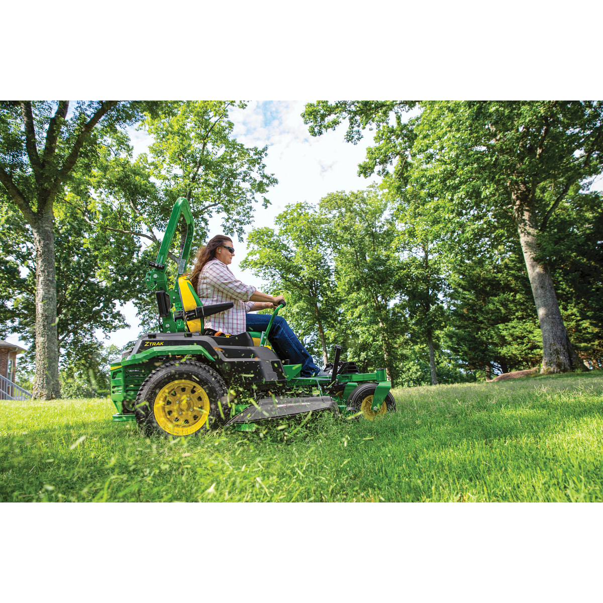 Side view of an operator using the Z530R ZTrak™ Mower on a tree-edged lawn