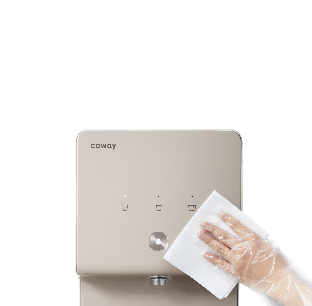 Hand wearing a transparent glove wiping the front panel of a beige Coway P-6320L water purifier with a white cloth.