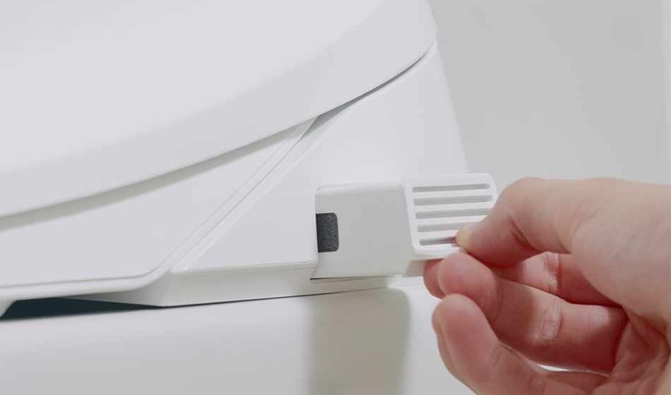 Hand pulling out a white plastic lever or tab from Coway BA-42A bidet.