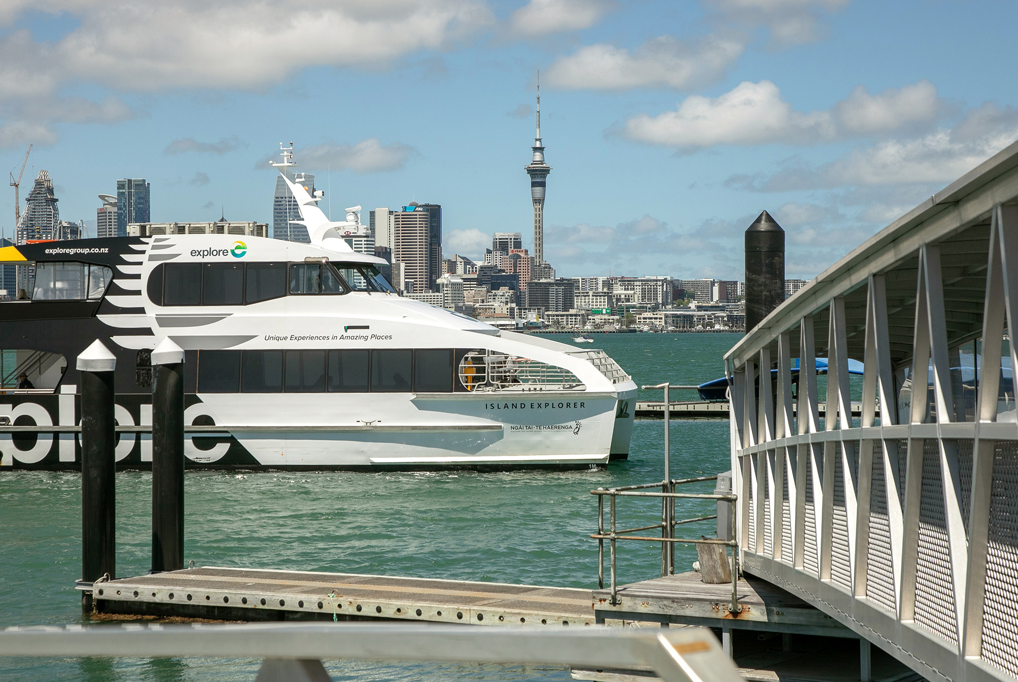 A ferry at the Bayswater pier with the Sky Tower behind
