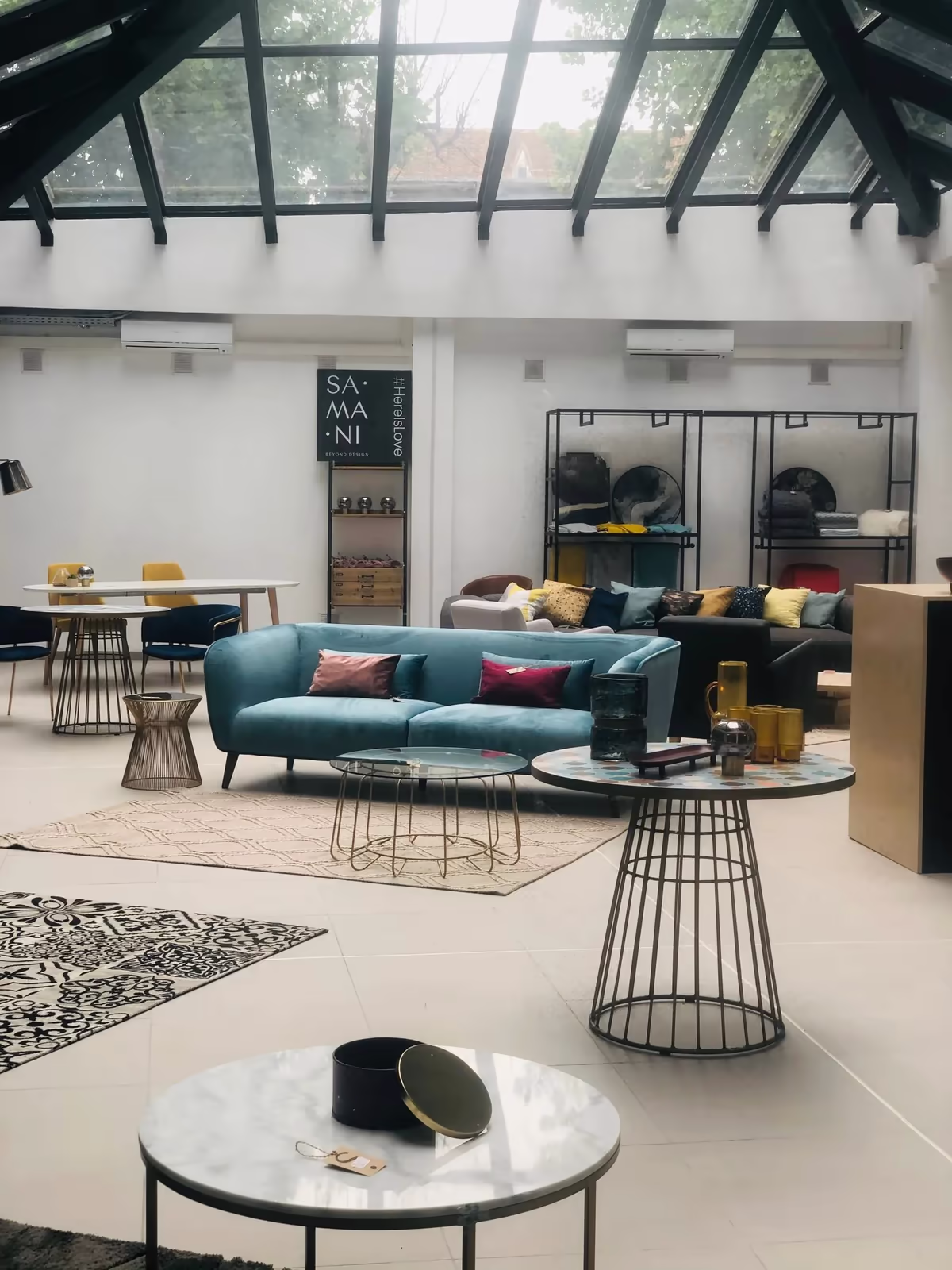 Le showroom d’un revendeur multimarque : canapé bleu, tables d’appoint et luminaires.