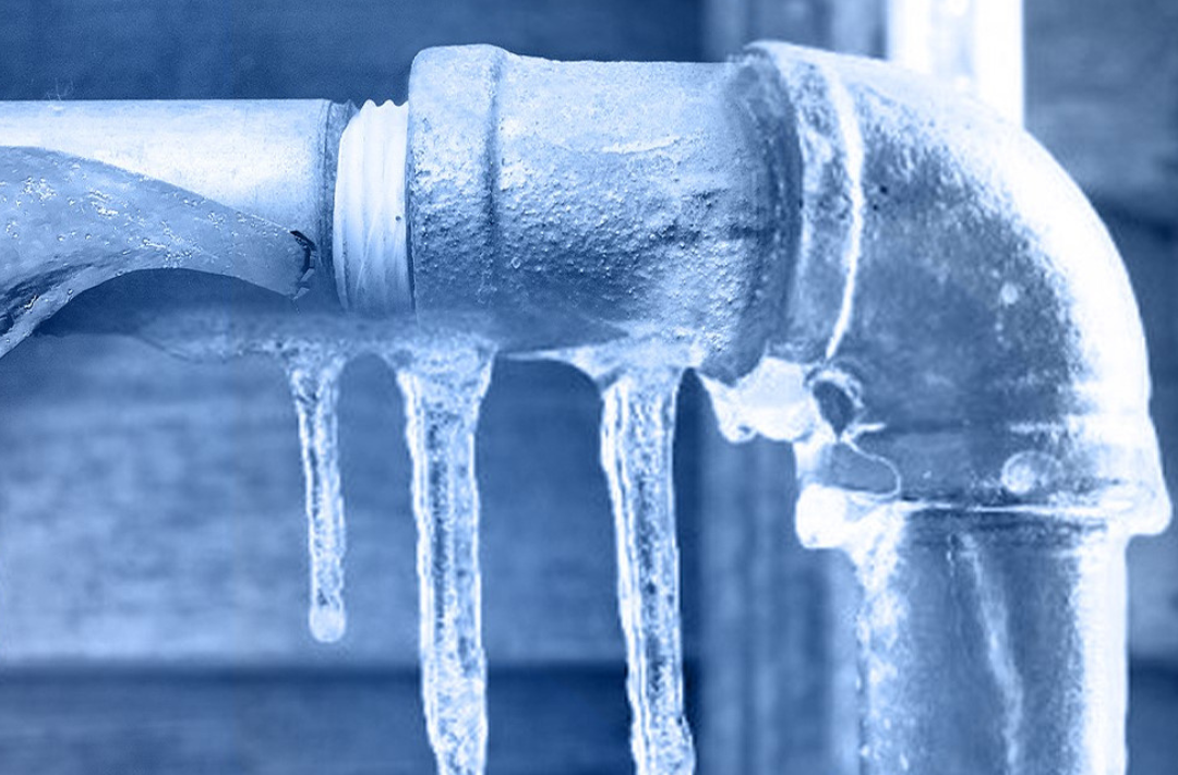 Close-up of frozen metal pipe with icicles, illustrating frozen pipe water damage repair services in Calgary