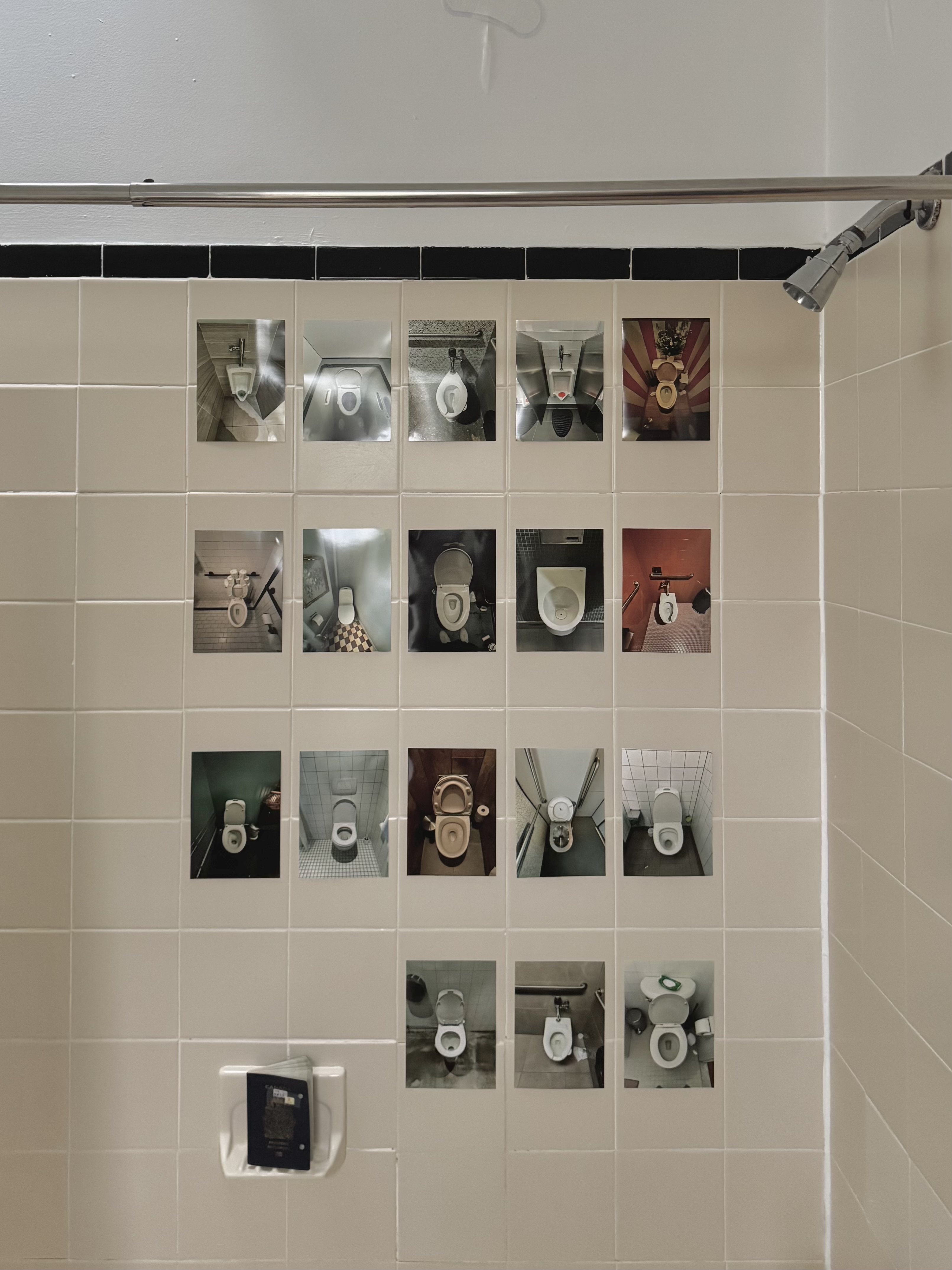 Beige tiled wall with 18 small photos of various toilet bowls arranged in a grid, beneath a showerhead and curtain rod.