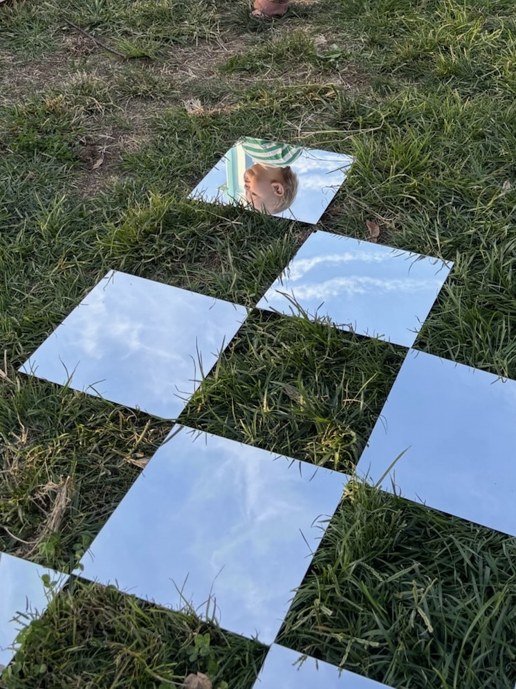 Small white sanitary pad on a white wall above black and beige tiles.