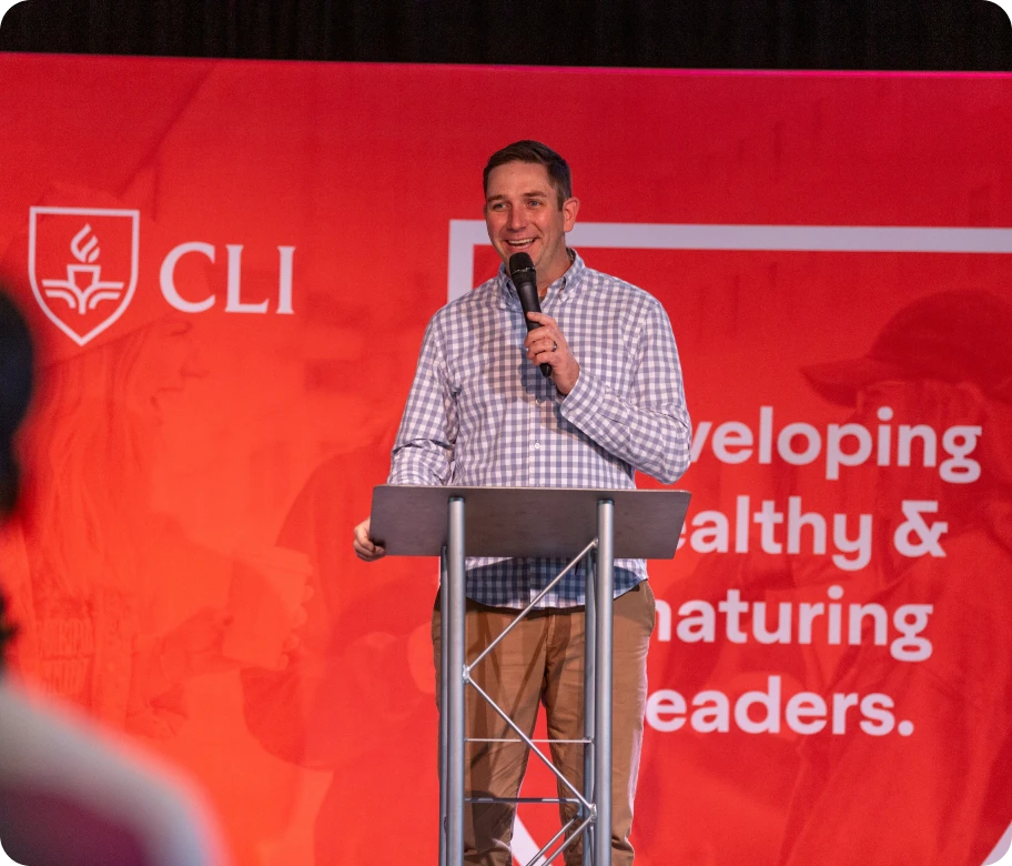 A speaker stands at a podium in front of a red backdrop, emphasizing themes of leadership and development.