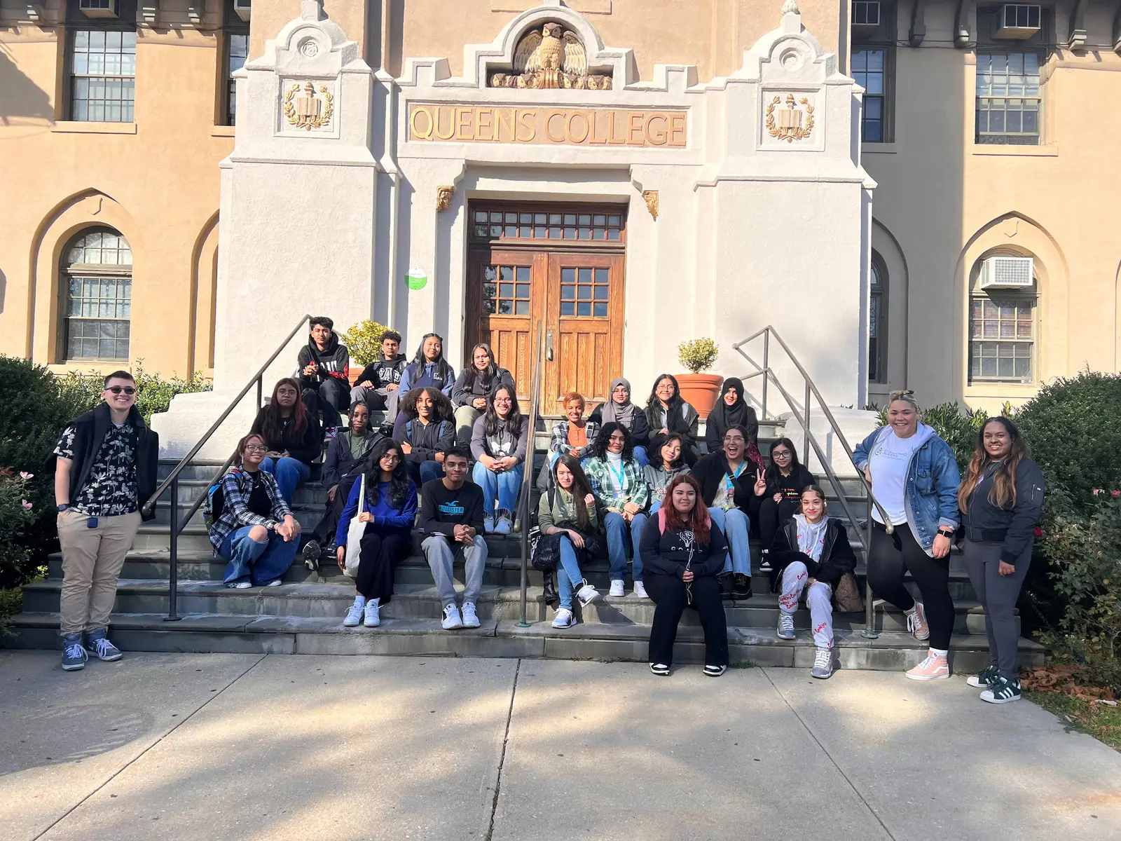 Students posing on steps outside Queens College entrance during visit