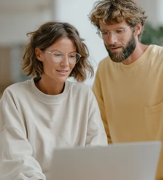 A woman and a man wearing glasses looking at a laptop together.