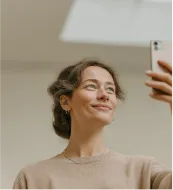 Person using a vacuum cleaner to clean office carpet near desks and chairs.