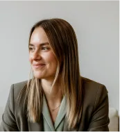 Three masked cleaning staff mopping the floor in a living room with a gray sofa and plant.