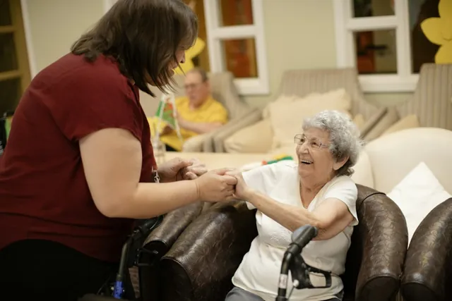 A caregiver and an older adult smiling together