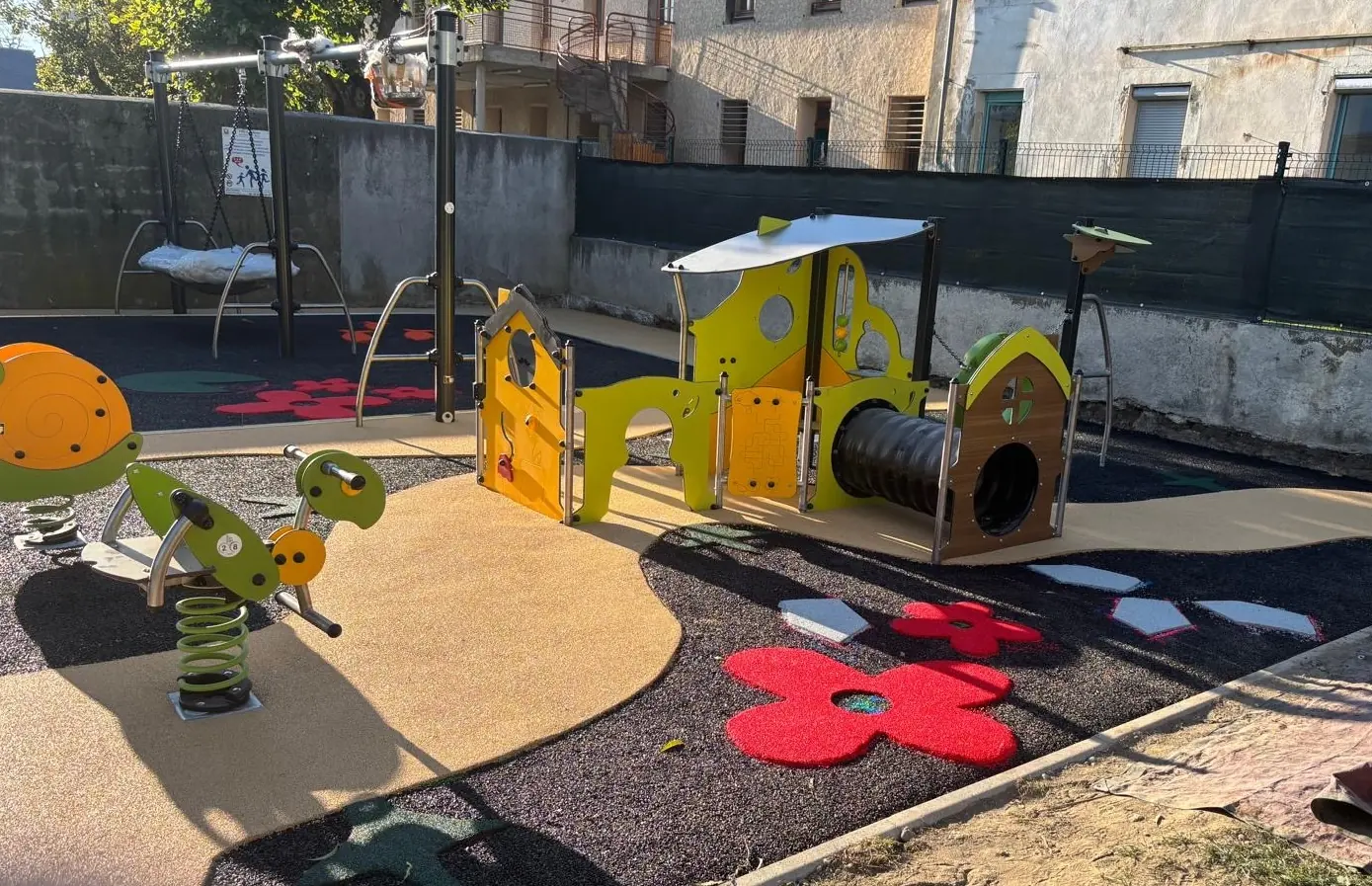 Aire de jeux de crèche avec sol amortissant sable et fleurs rouges sur sous-couche noire