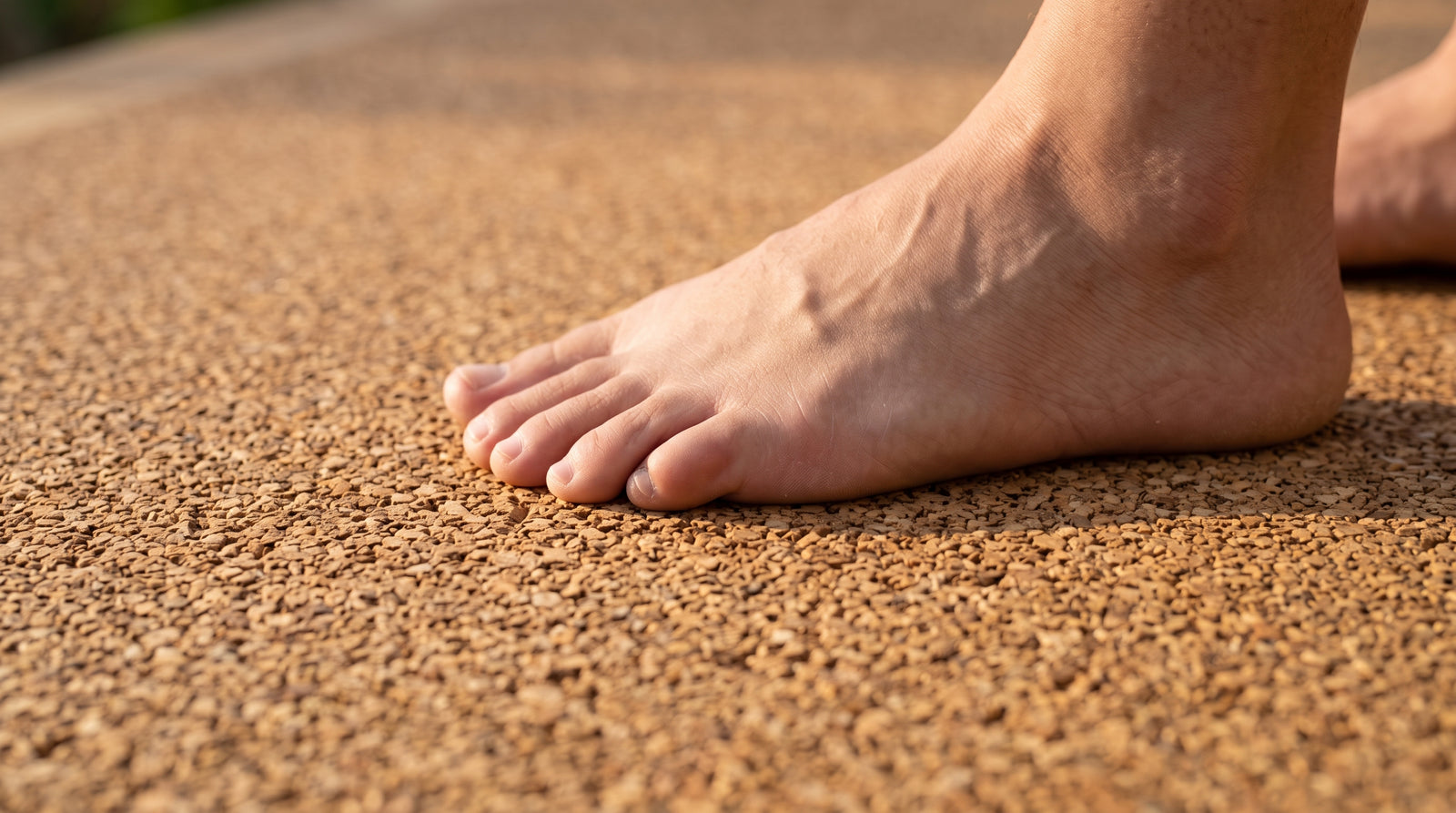 Finition en granulat de liège fin d'un sol amortissant, avec un pied nu posé dessus