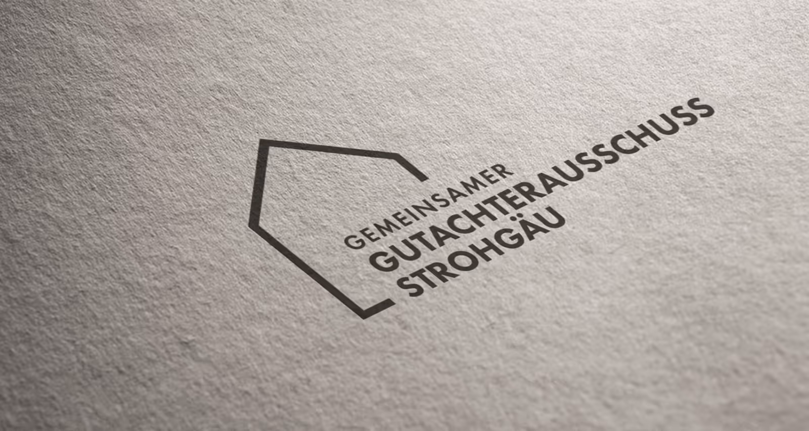 Logo with an abstract house outline and the text 'GEMEINSAMER GUTACHTERAUSSCHUSS STROHGÄU' printed on textured paper.