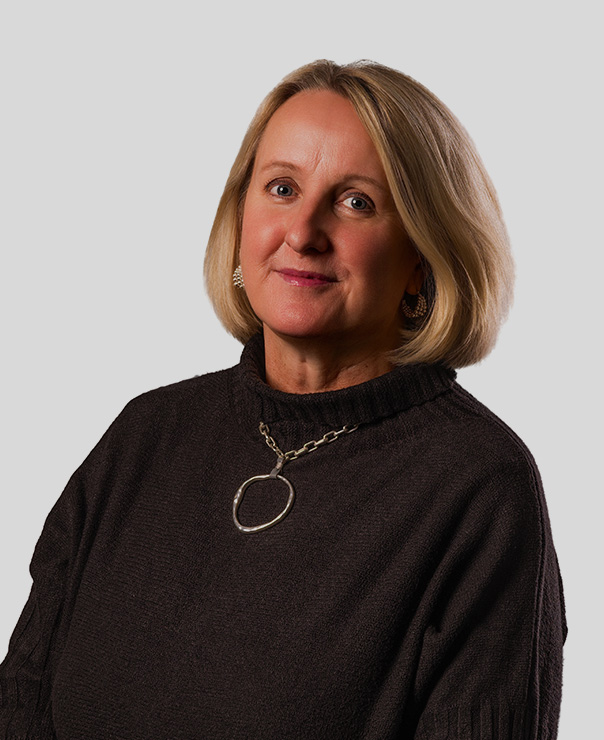 Woman with blonde bob haircut in black sweater wearing circular silver pendant necklace and earrings.
