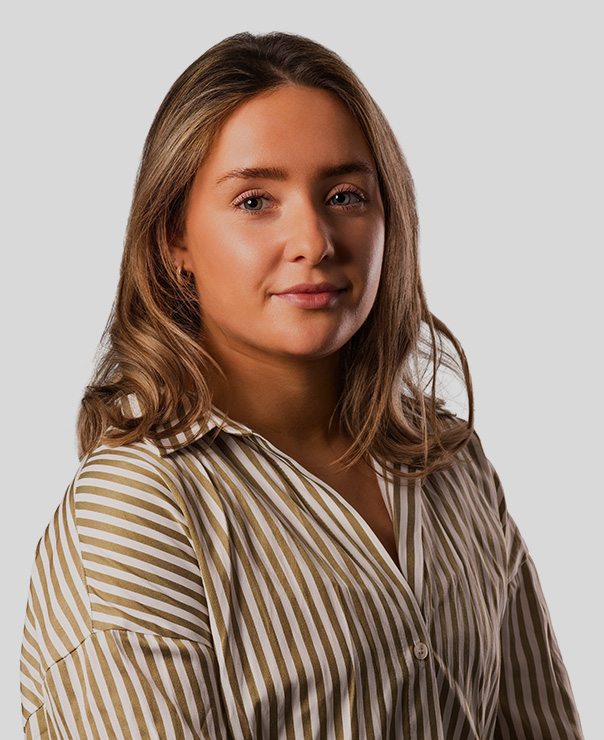 Woman with light brown hair wearing a beige and white striped shirt against a gray background.