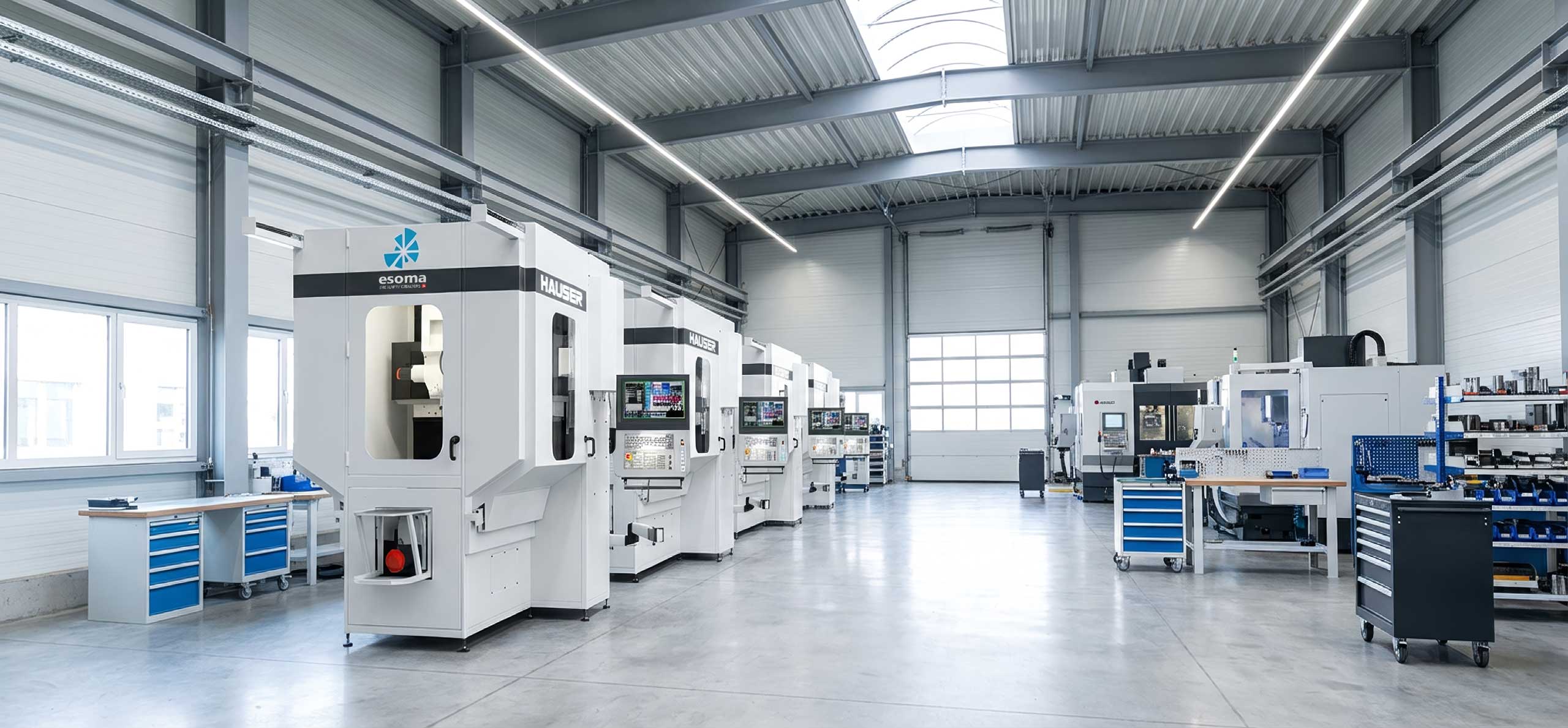 Helle, saubere Fabrikhalle mit mehreren modernen CNC-Maschinen und Arbeitsstationen.