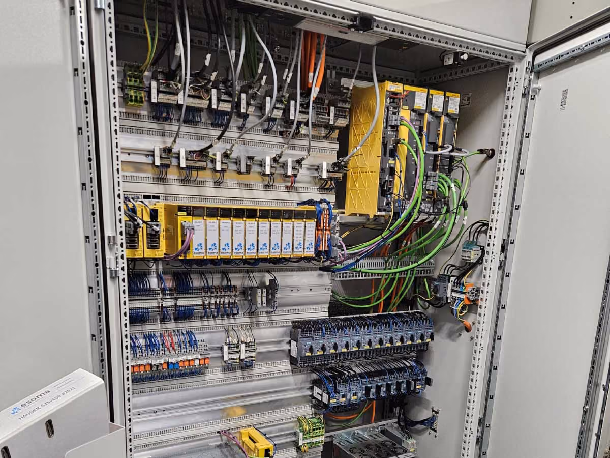 Geöffneter elektrischer Schaltschrank mit verdrahteten Steuerungs- und Sicherungskomponenten.