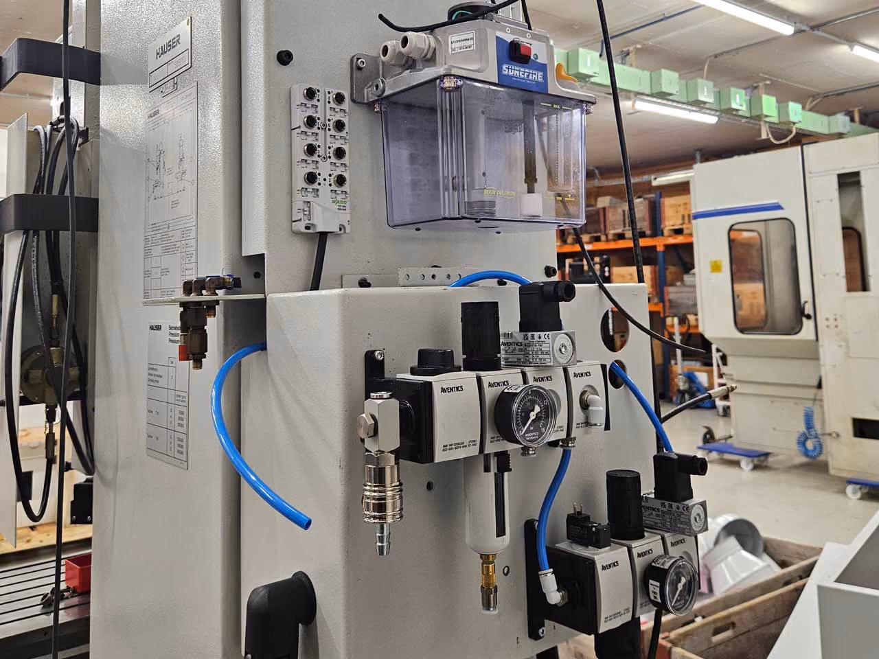 Industrielle Steuerungseinheit mit Ventilen, Messgeräten und blauen Schläuchen in Werkstatt.