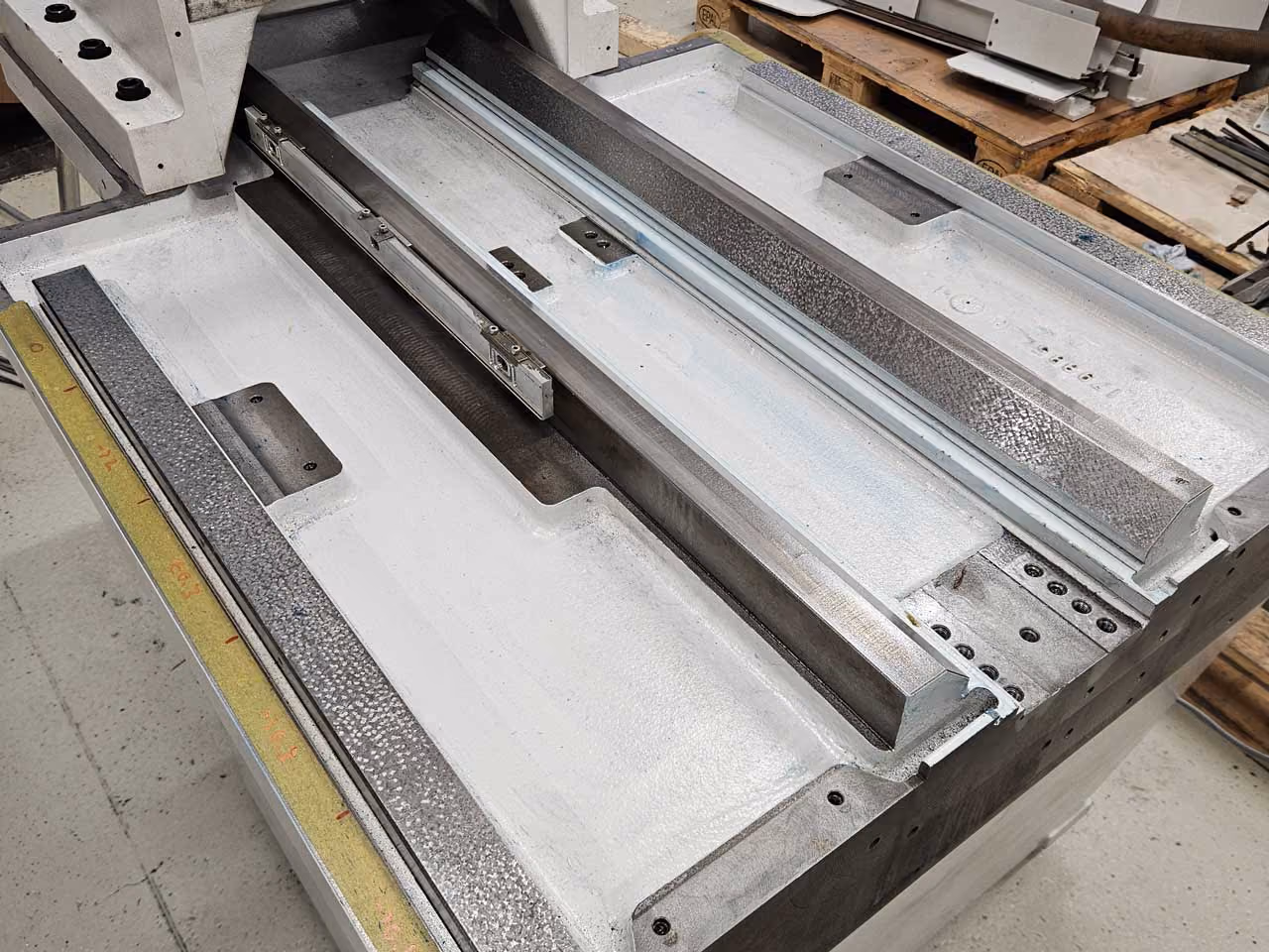 Metallmaschine-Teil mit Schienen und präzisen Führungselementen in einer Werkstatt.