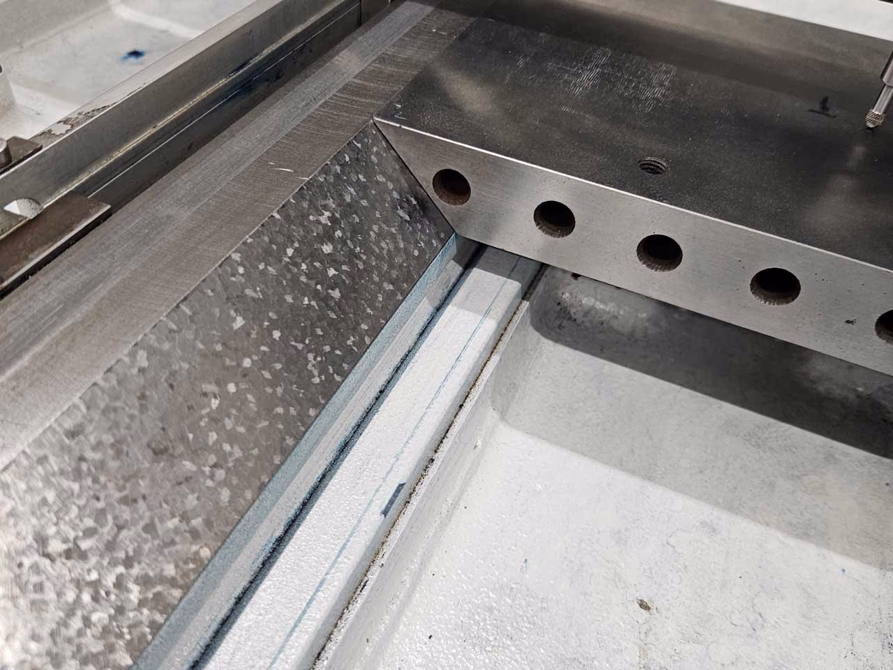 Nahaufnahme einer mechanischen Vorrichtung mit Metallplatten und mehreren runden Löchern.