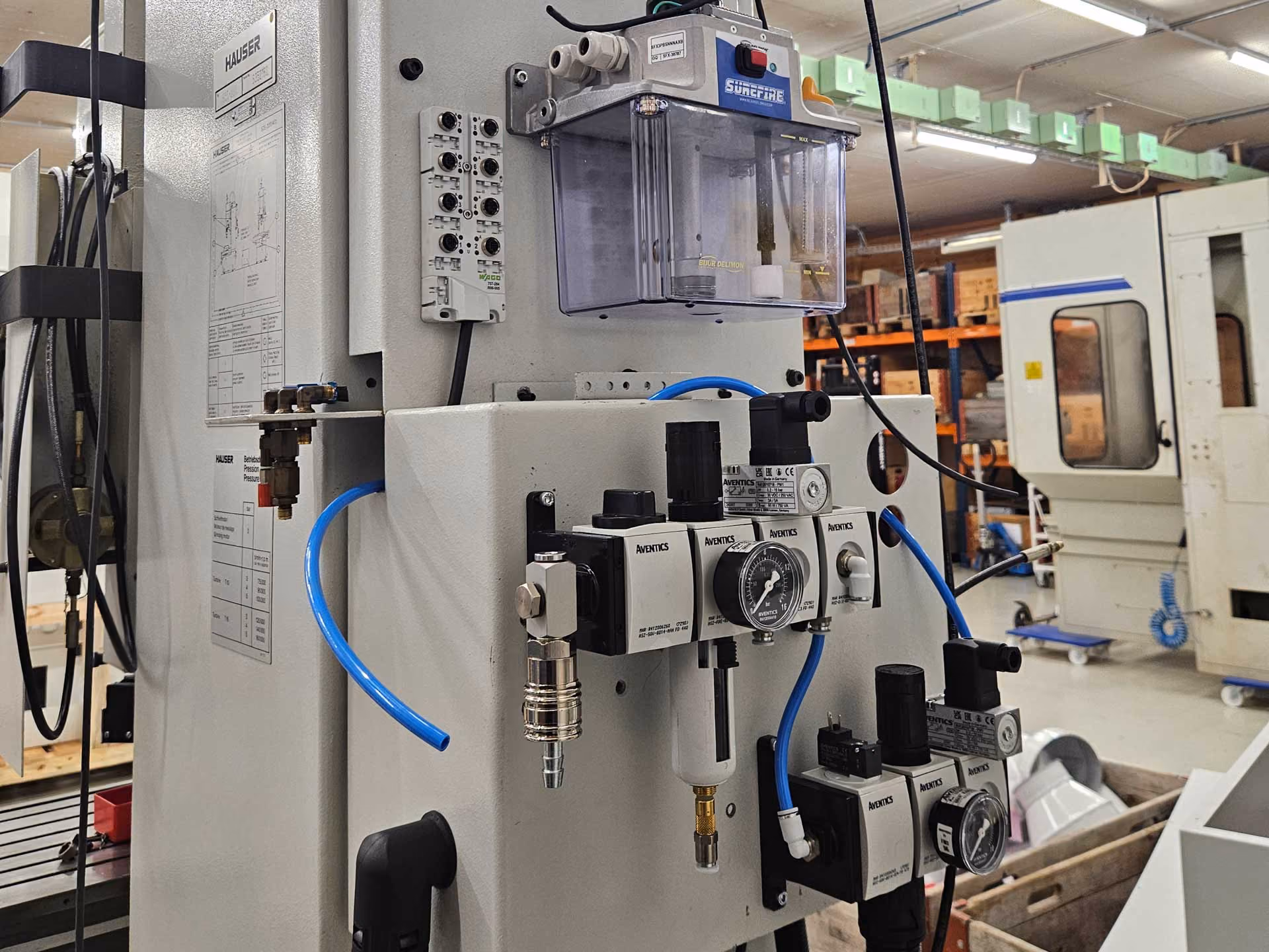 Industrieanlage mit pneumatischer Steuerung und blauen Schläuchen in einer Werkstatt.