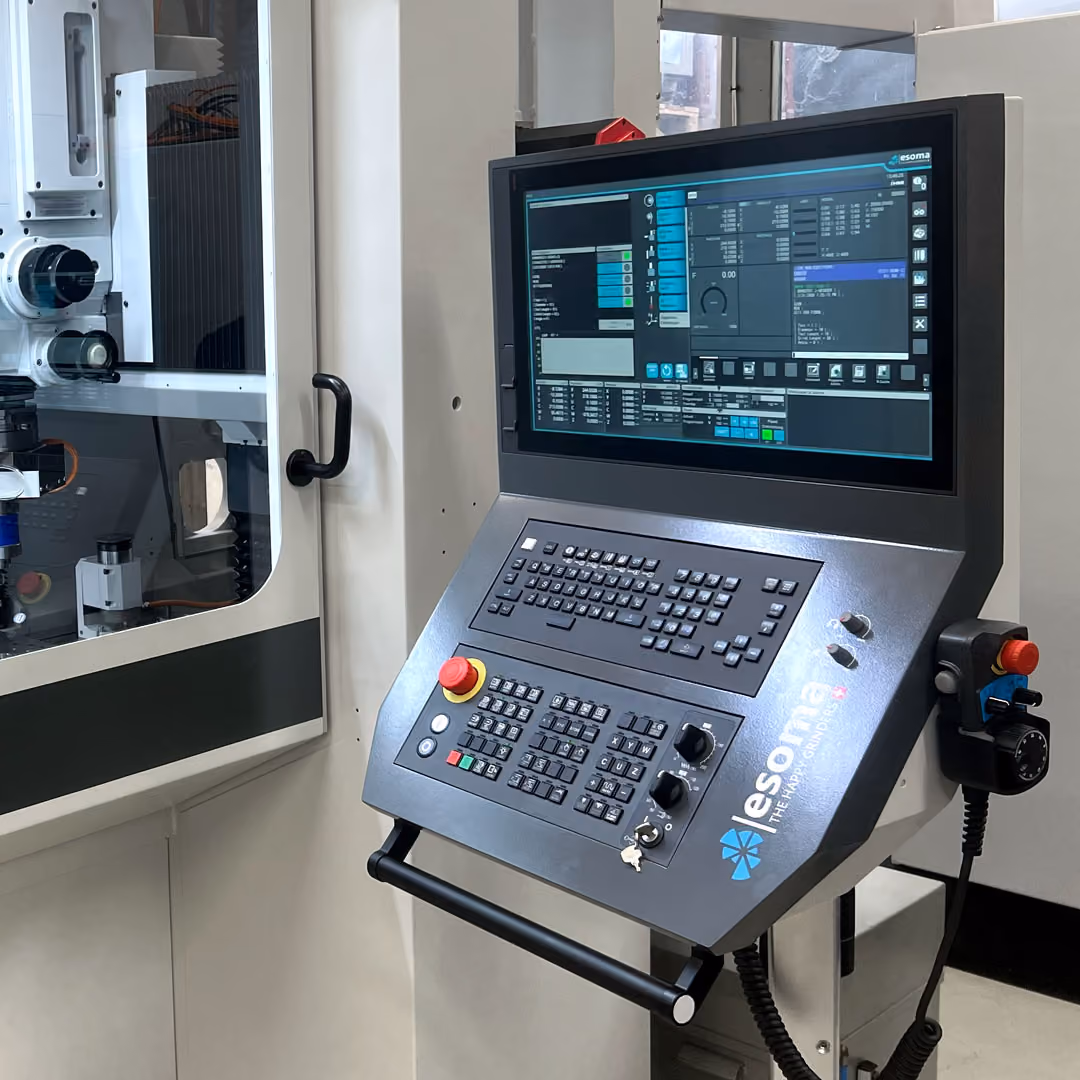 Industrielle Steuerungseinheit mit Bildschirm und Tastatur neben Fertigungsmaschine.
