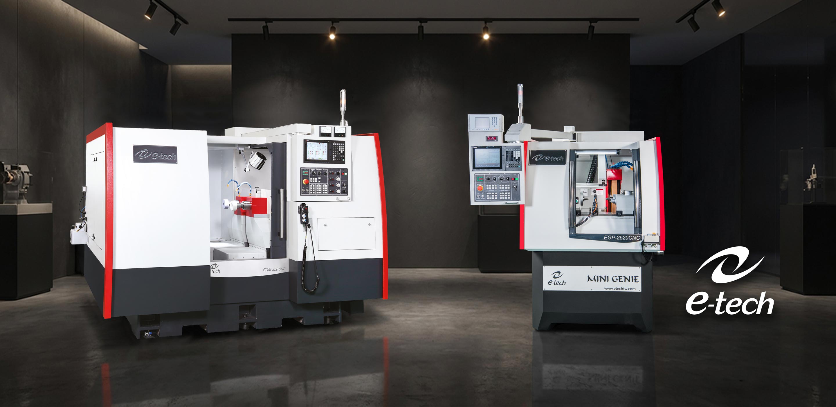 Zwei CNC-Maschinen mit Steuerpanelen in einem modernen, dunklen industriellen Raum.