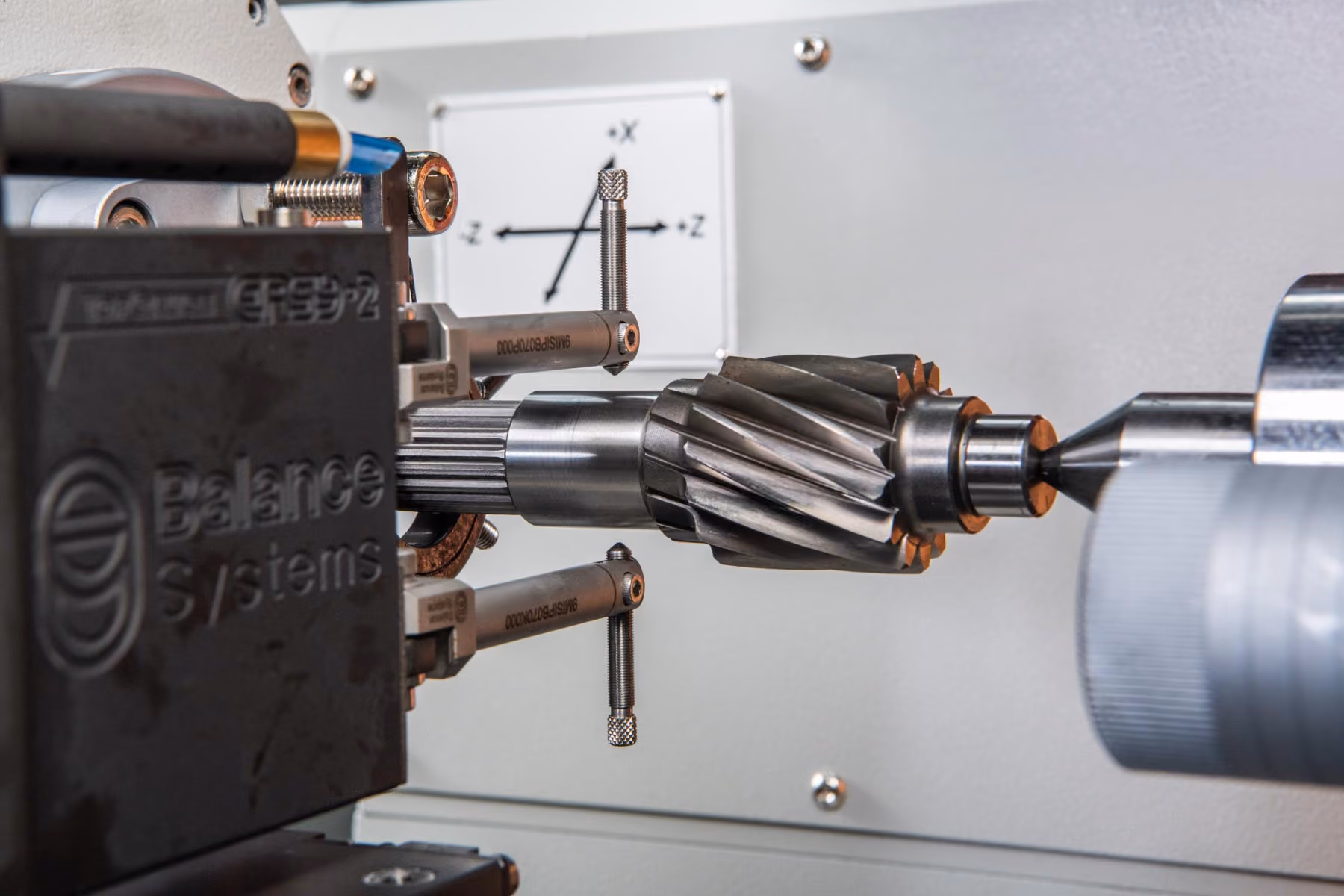 Metallwelle mit Zahnrad wird in Maschine für präzises Auswuchten gehalten und gemessen.