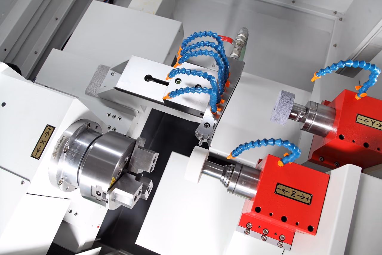 Industrielle Schleifmaschine mit rot lackierten Haltern und flexiblen blauen Kühlmittelschläuchen.